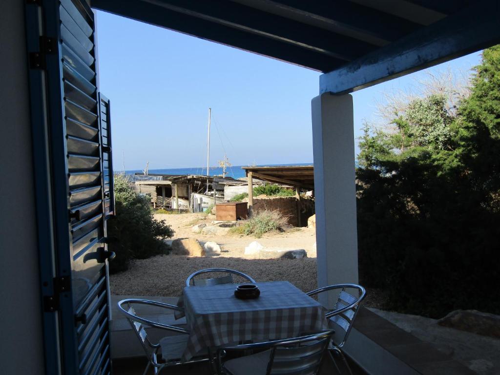 una mesa y sillas en un porche con vistas en VIVIENDAS TURISTICAS CAN MARIANO BARBER - ES CALÓ - FORMENTERA en Es Calo