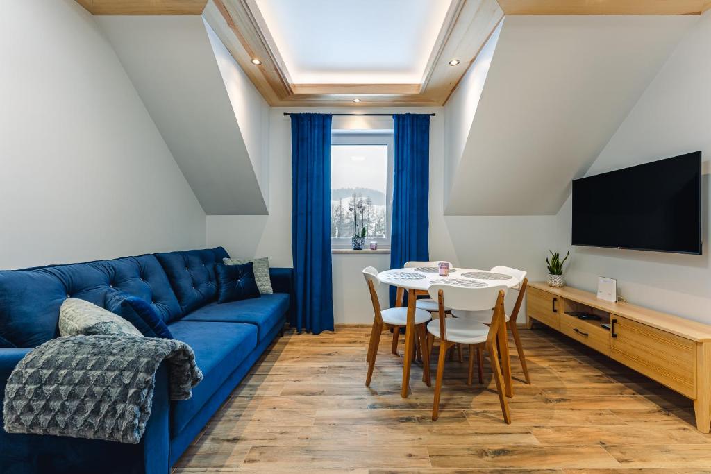 a living room with a blue couch and a table at Apartament Między Górami in Kacwin