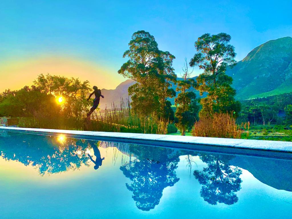 um homem correndo por uma piscina com montanhas ao fundo em The Guardian Hermanus Luxury Self-Catering Hemel en Aarde Valley em Hermanus