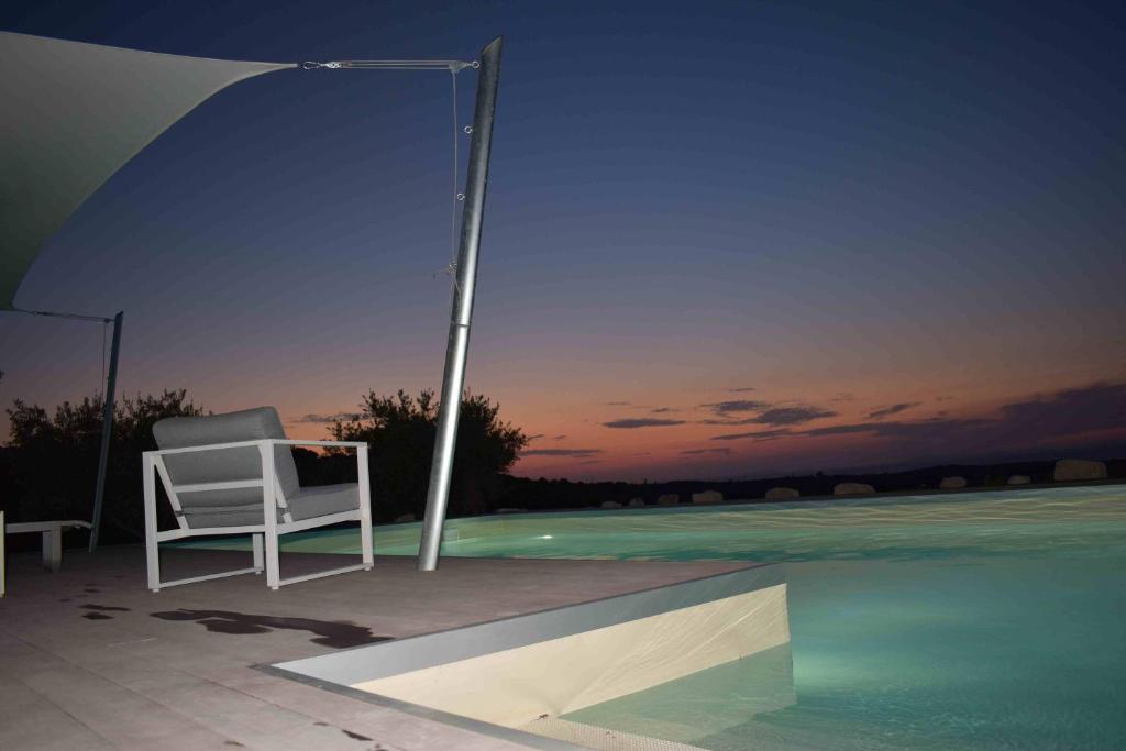 een witte stoel op een patio naast een zwembad bij CASA MARE e TRAMONTO in Monte Marzeddu