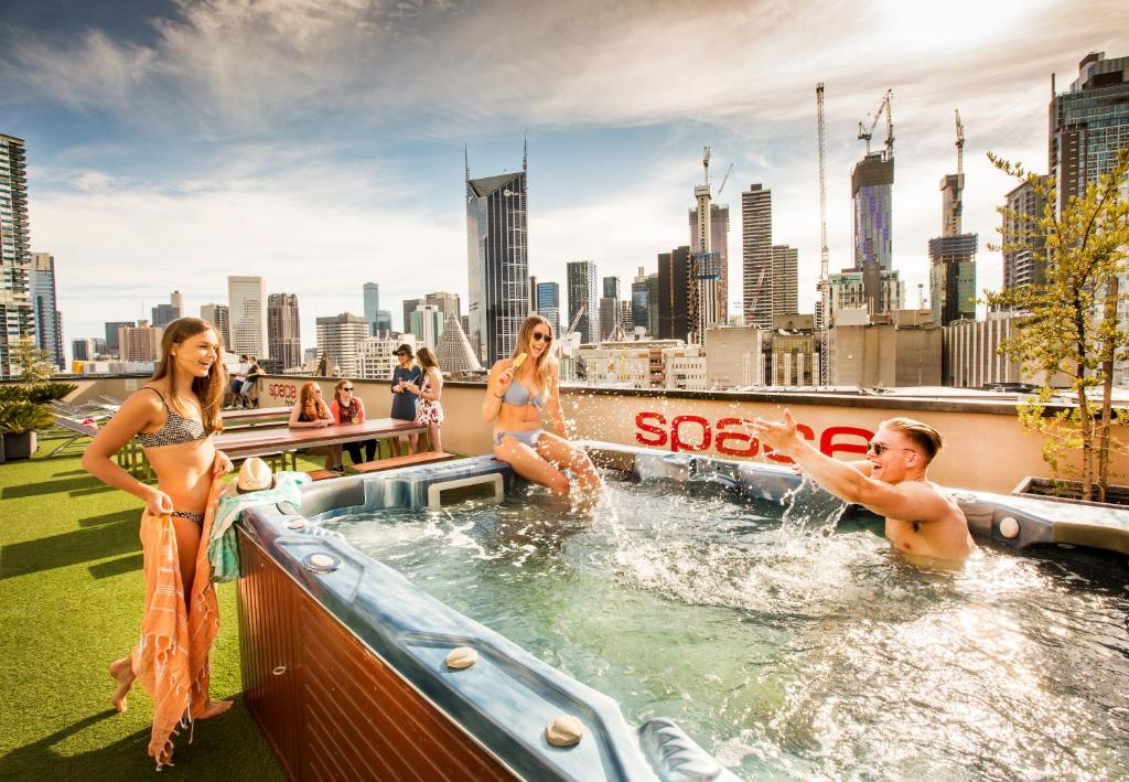 um grupo de pessoas em uma banheira de hidromassagem com um horizonte da cidade em Space Hotel em Melbourne