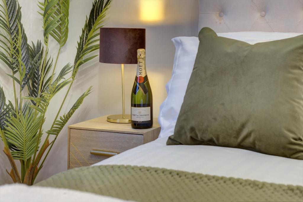 Una botella de vino en una mesita de noche junto a la cama en Kist Accommodates - Stylish Headingley Apartment - Parking - 500 mps WIFI, en Meanwood