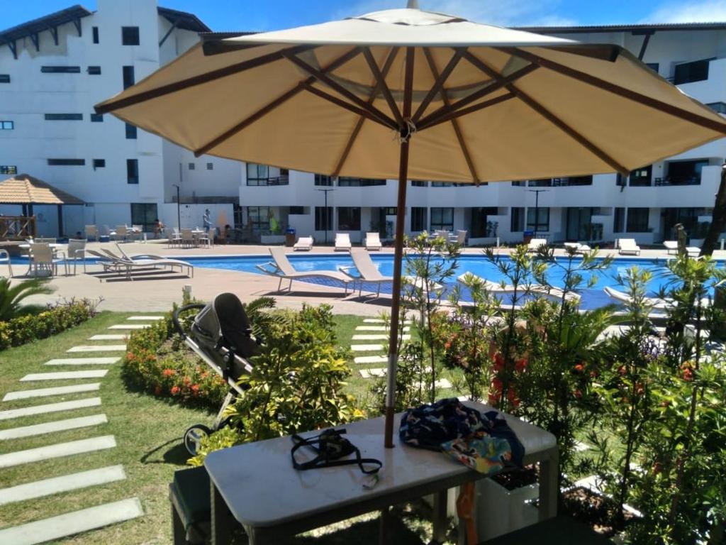 - une table avec un parasol en face de la piscine dans l'établissement Mauí beach resort, à Tamandaré
