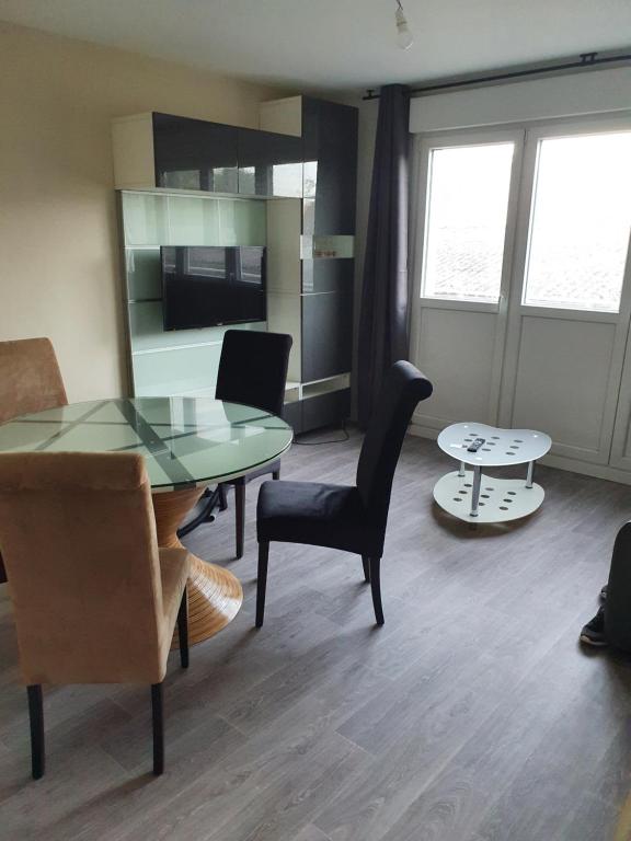 uma sala de estar com uma mesa de vidro e cadeiras em Appartement 2 chambres, proximité plage, commerces et centre ville em Dunkerque