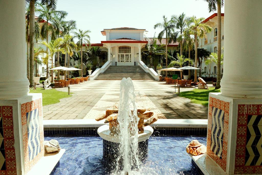 une fontaine en face d'un bâtiment avec des palmiers dans l'établissement Quinta Edén Villahermosa, à Villahermosa