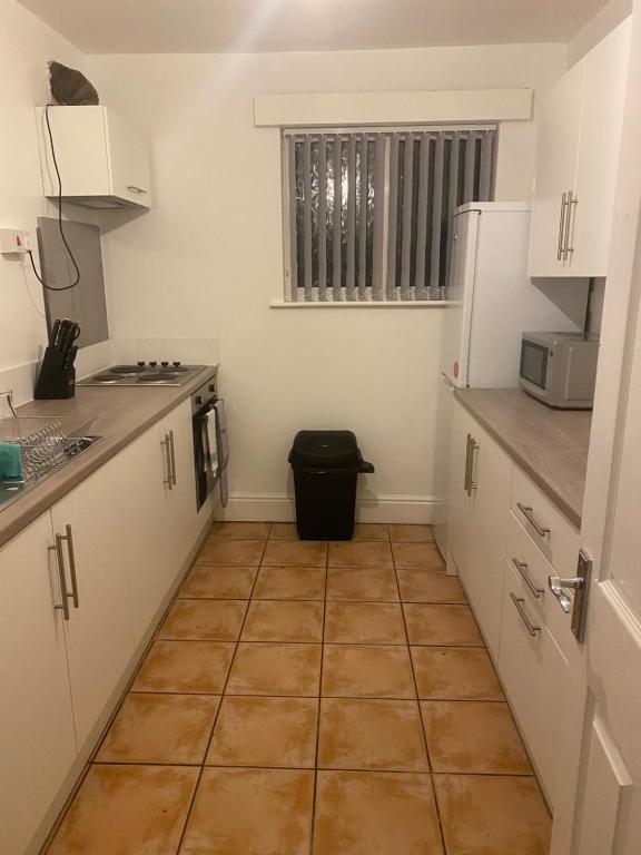 uma cozinha com armários brancos e piso em azulejo em Smith House em Scunthorpe