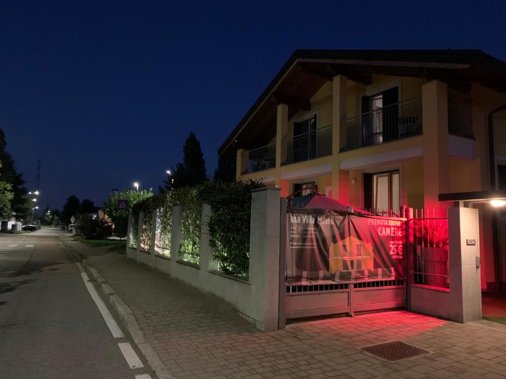 una casa con una recinzione rossa di fronte a una strada di Rhospitality - B&B Villa Milano a Cornaredo