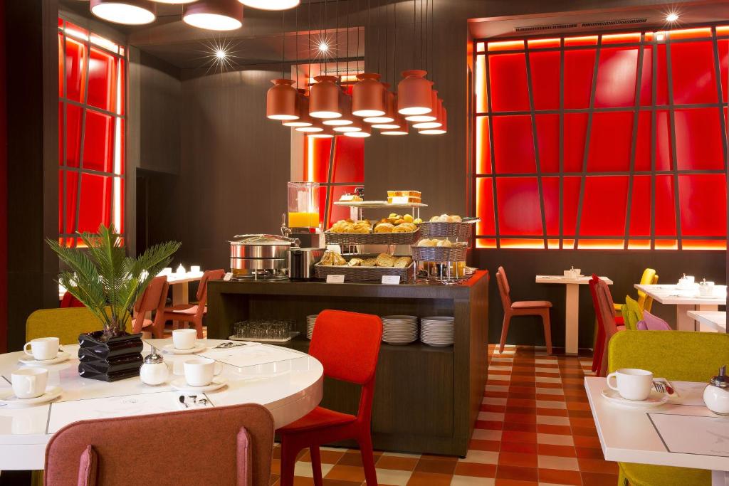 a dining room with tables and chairs and red windows at Hotel D - Strasbourg in Strasbourg