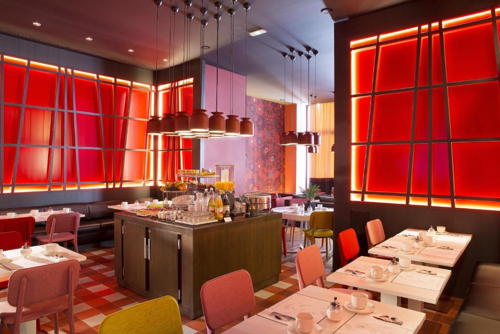 ein Restaurant mit Tischen, Stühlen und roten Wänden in der Unterkunft Hotel D - Strasbourg in Straßburg
