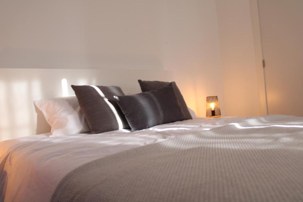 1 cama con almohadas blancas y negras y lámpara en Arco´s Apartment 1, en Ponta Delgada