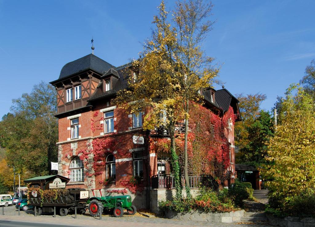 una gran casa de ladrillo con un tractor verde delante de ella en Braugasthof Papiermühle en Jena