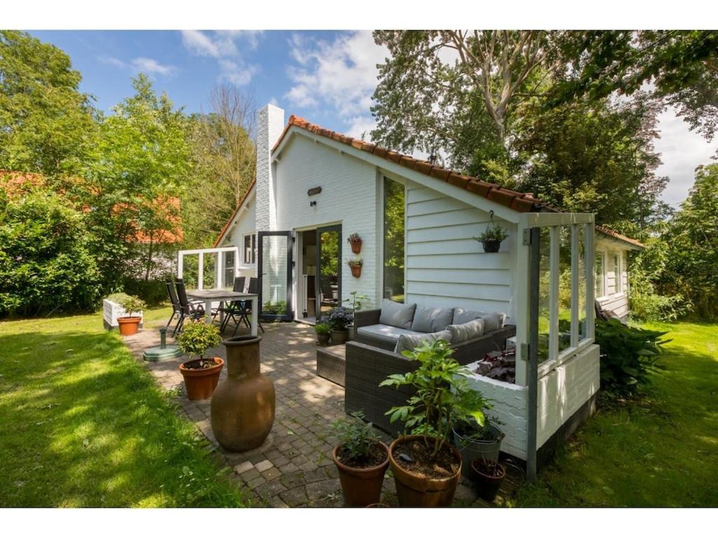 een klein wit huis met een bank in een tuin bij Tranquil holiday home in Dishoek with garden in Dishoek