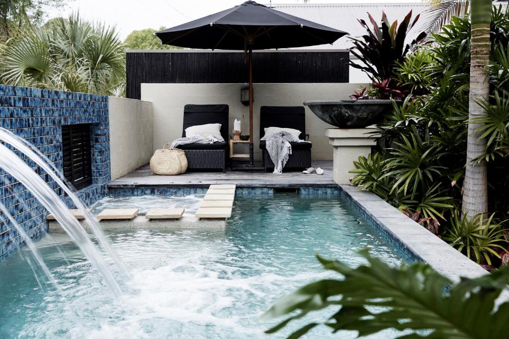 a swimming pool with an umbrella and a fountain at The Villas of Byron in Byron Bay