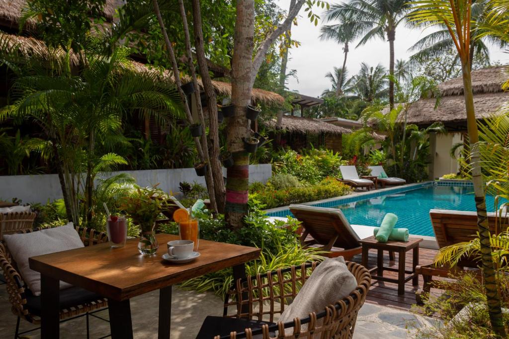 un patio con mesa y sillas junto a una piscina en Amaya Boutique Resort, en Srithanu