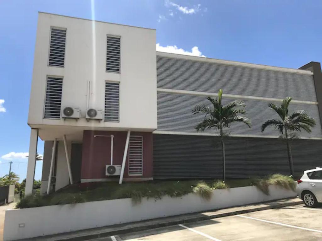 un edificio con un coche aparcado en un aparcamiento en Meublé de standing au coeur des commodités en Schœlcher