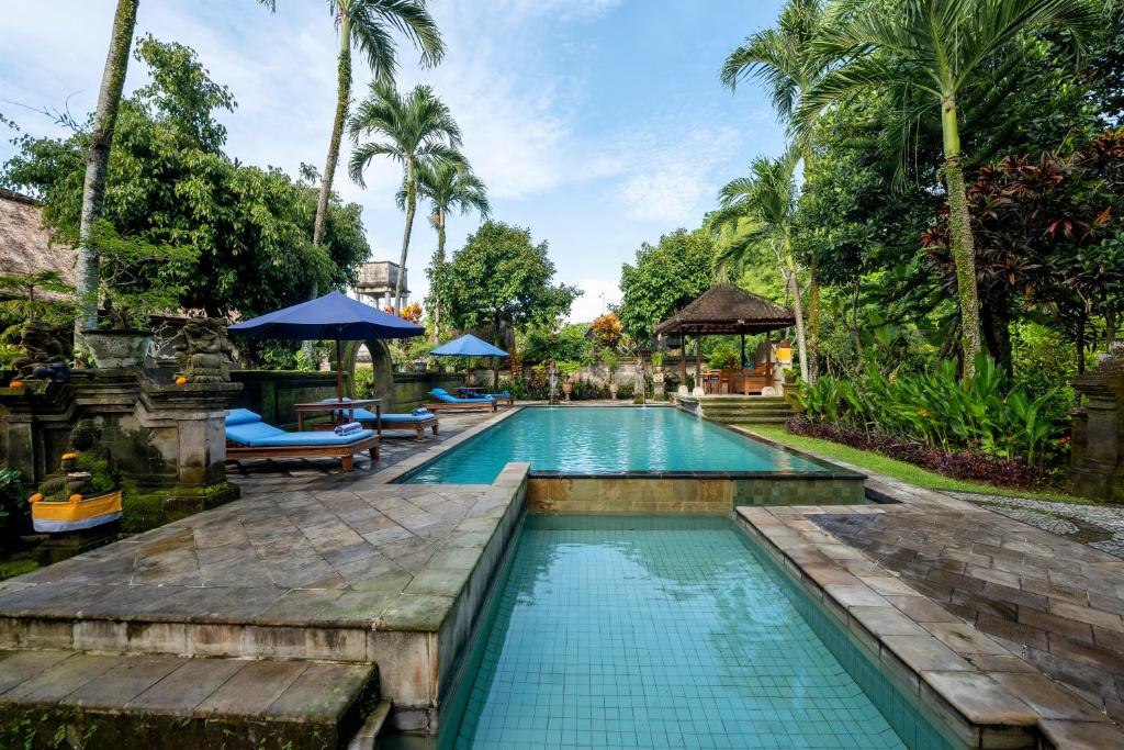 a swimming pool at a resort with palm trees at Alam Jiwa Ubud in Ubud