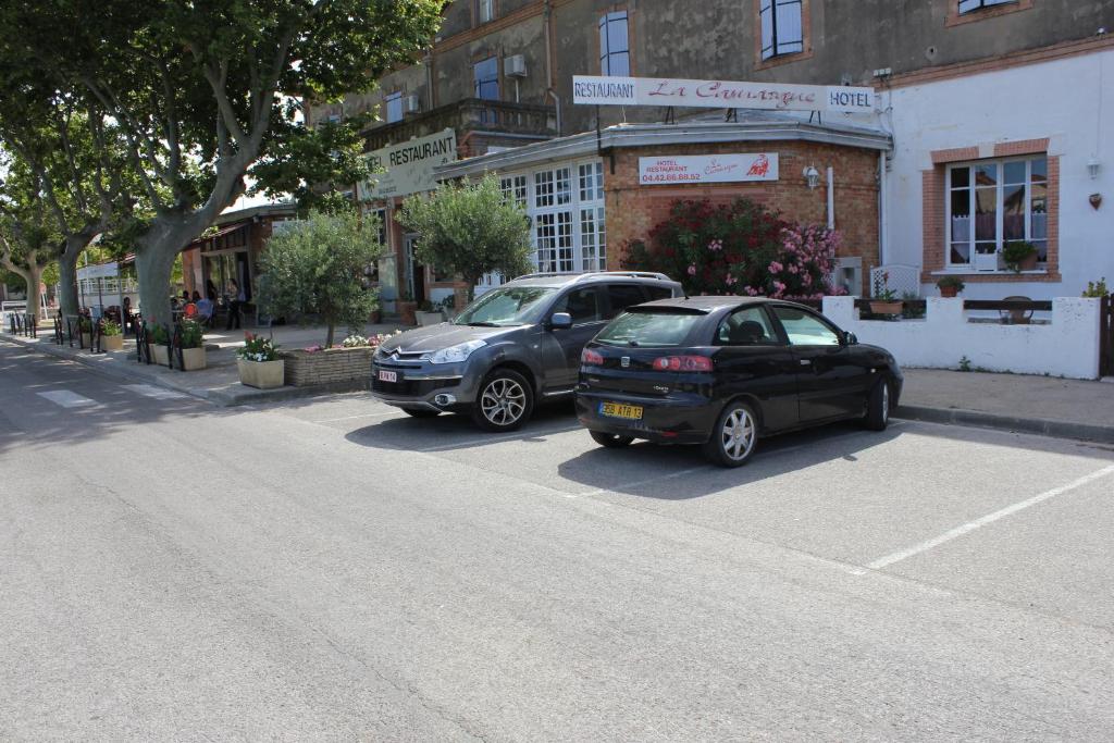 two cars parked in a parking lot on a street at Hotel Restaurant La Camargue in Salin-de-Giraud