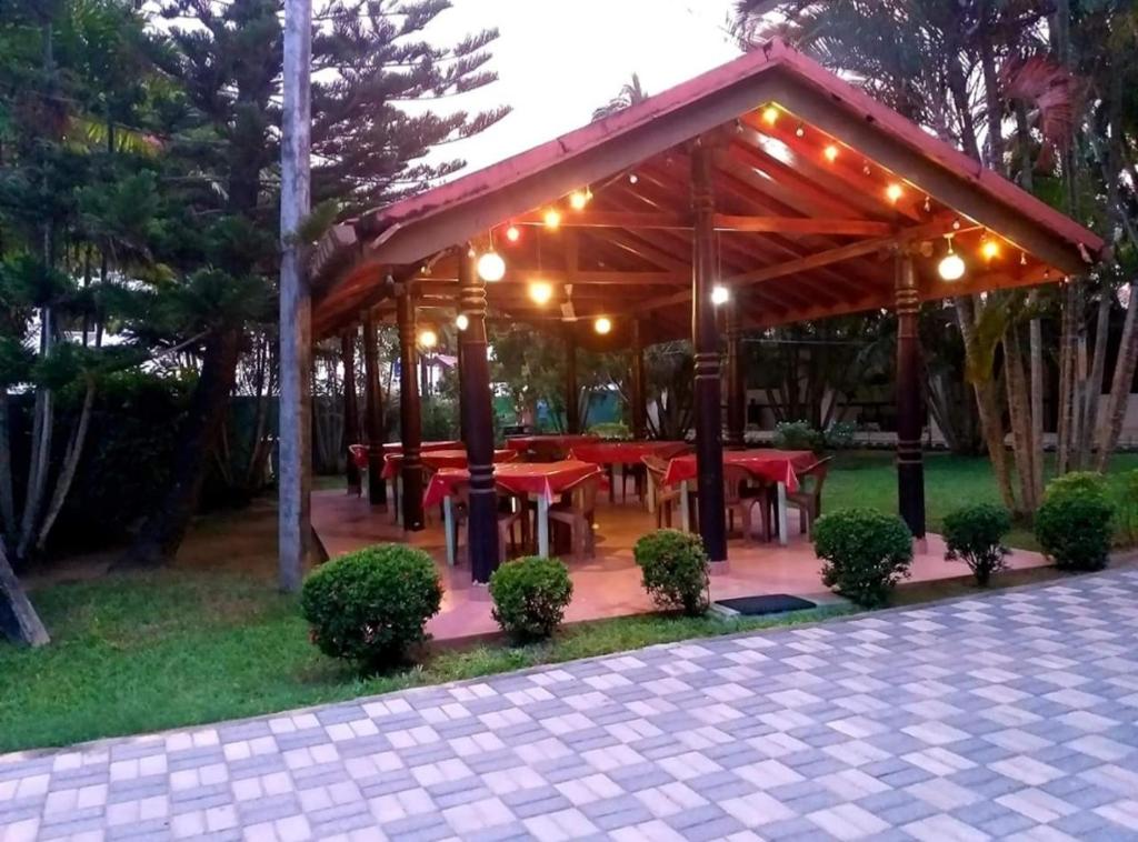 a wooden pavilion with red tables in a park at Hotel TK Green Garden in Matara