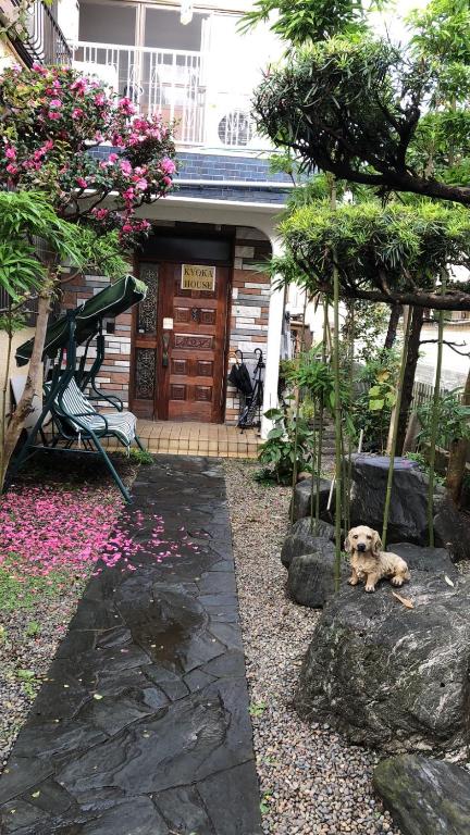 a dog sitting in front of a building with flowers at kyoka house練馬 in Tokyo