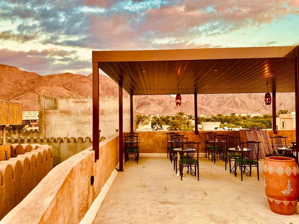 a patio with tables and chairs and a view of the desert at Jawharat Alaqar Inn نزل جوهرة العقر in Nizwa