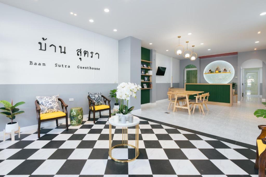 a room with a checkered floor and a table and chairs at Baan Sutra Guesthouse in Phuket Town