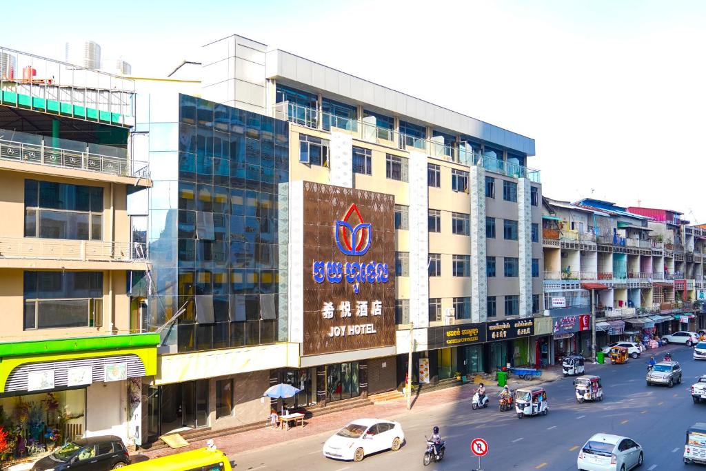 Joy Hotel في بنوم بنه: شارع المدينة مزدحم مليء بالسيارات والمباني