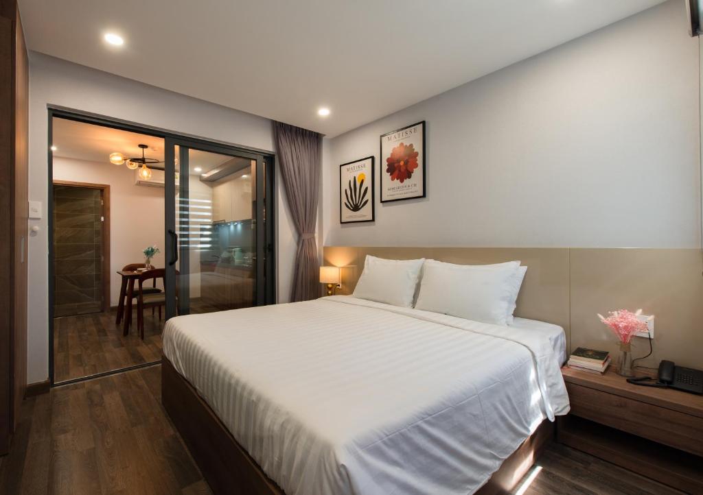 a bedroom with a large white bed and a bathroom at The Anchor Apartment - Nha Trang in Nha Trang