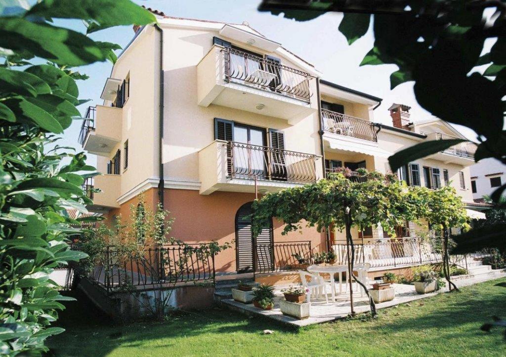 a large building with balconies and trees in front of it at Apartments Alice in Rovinj