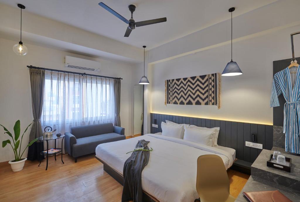 um quarto de hotel com uma cama grande e uma cadeira em Poshtel VNS em Varanasi