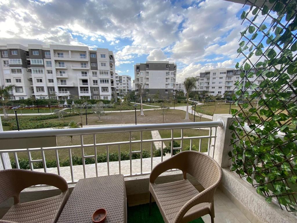 balcón con 2 sillas y vistas a los edificios en Madinaty Well-furnished 3- Bedroom apartment - شقة فندقيه للايجار مدينتي, en Madīnat ash Shurūq