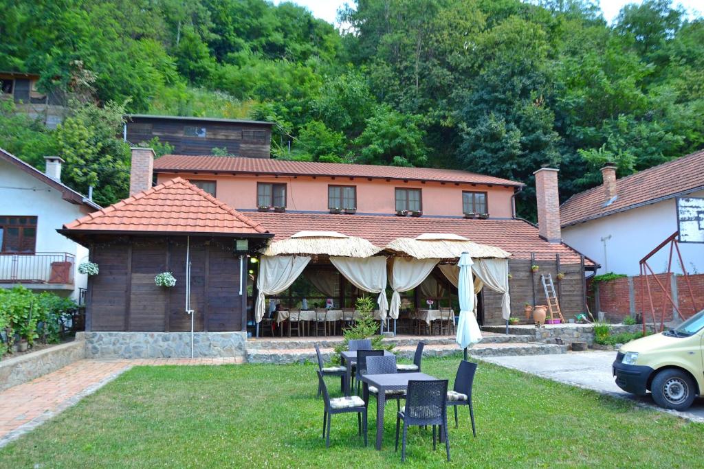 a house with a table and chairs and an umbrella at Podrum Miljević in Ledinci