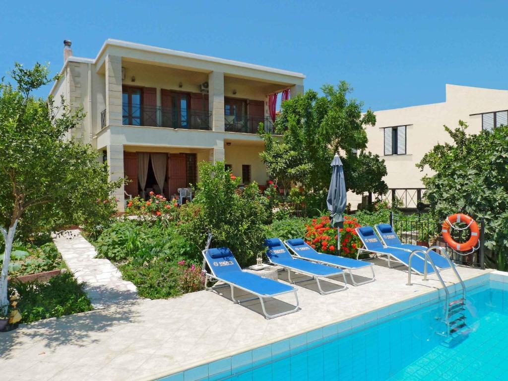 a house with a swimming pool with chairs and an umbrella at The Garden Villas in Maleme