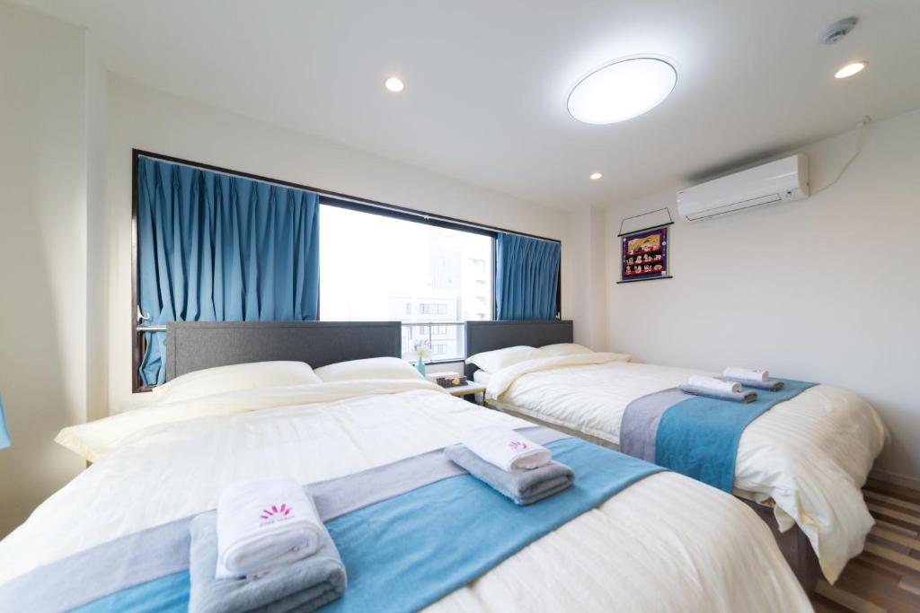 2 camas en una habitación con cortinas azules en High Five Guest House, en Tokio