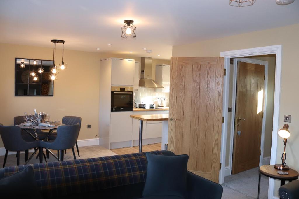 een woonkamer en een keuken met een bank en een tafel bij Canal view 2 bed picturesque cottage with log fire in Blisworth