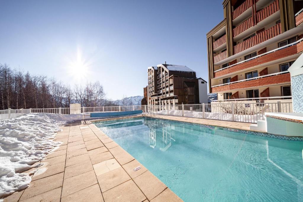 une piscine en face d'un bâtiment dans l'établissement Sejour au coeur de l Alpes d Huez dans un appartement moderne, à Huez