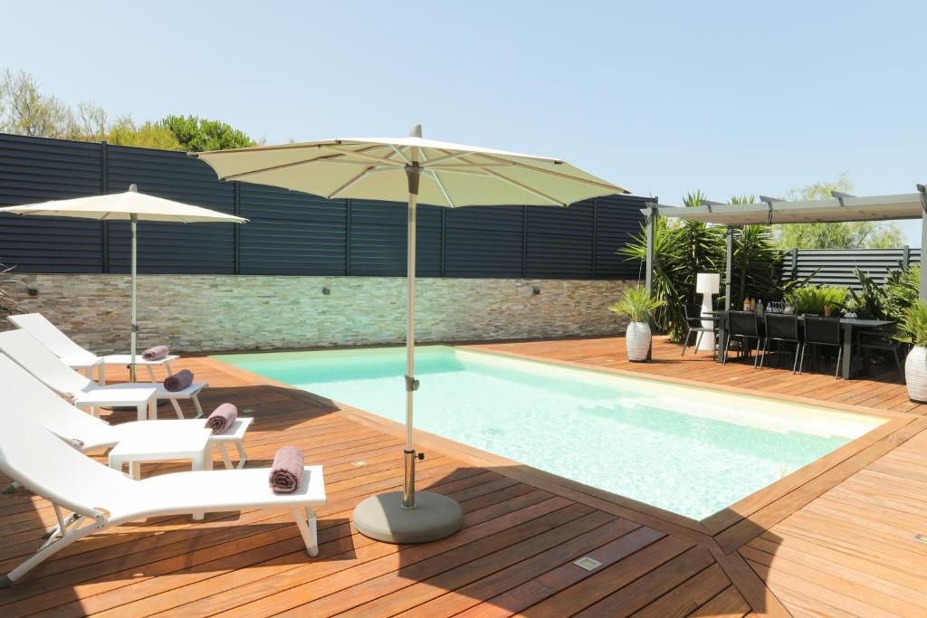 a pool with chairs and an umbrella on a wooden deck at Villa Marine en bord de mer... in Lumio