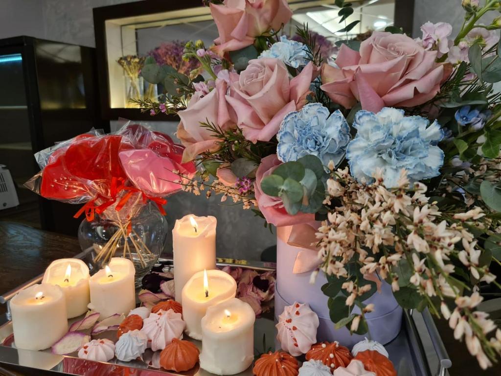 a group of candles and flowers on a table at Dostoevsky Hotel in Saint Petersburg