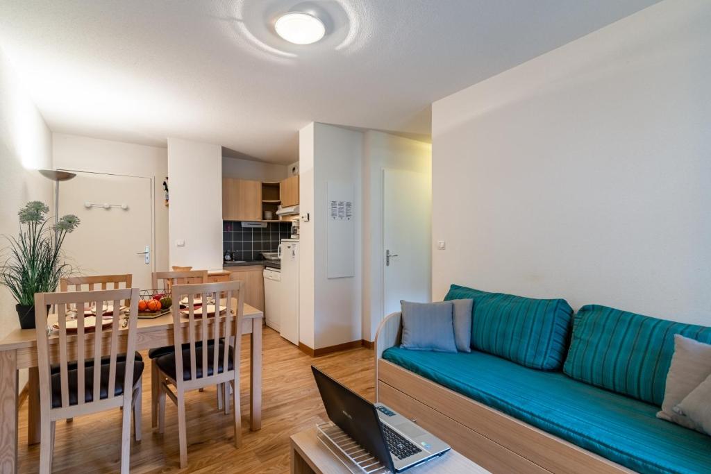 a living room with a blue couch and a table at Les Jardins de Ramel - Apt proche des pistes avec Wifi in Luchon