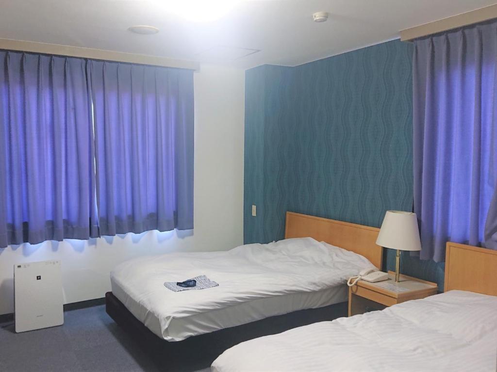 a bedroom with two beds and purple curtains at Bayside Hotel Ryugu / Vacation STAY 63714 in Anan
