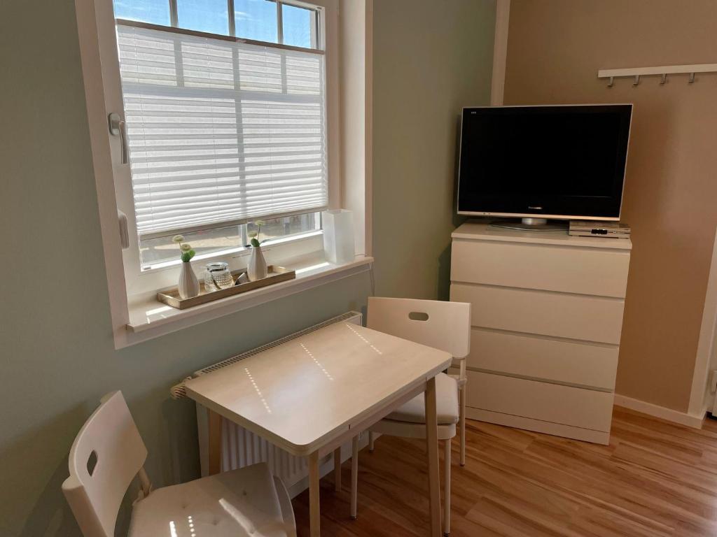 a small dining room with a table and a television at Ferienzimmer/wohnung am Kurstrand, WLAN in Zingst