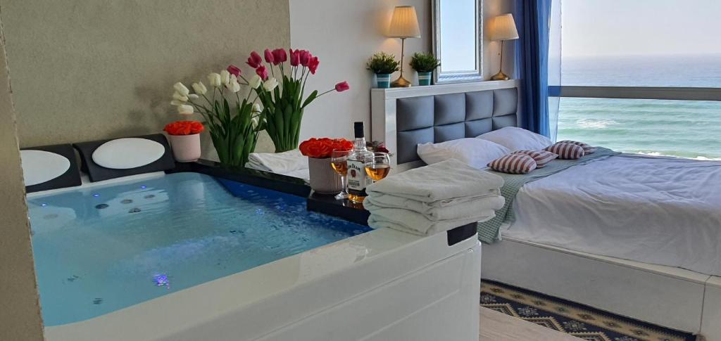 a bedroom with a tub with a bed and flowers at Royal suite with sea view- private jaccuzi-Also suitable for orthodox people in Netanya