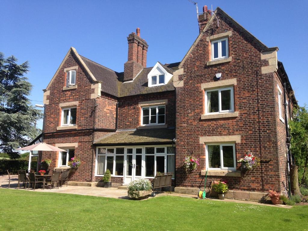 een groot bakstenen huis met een gazon ervoor bij Whitethorn Bed and Breakfast in Congleton