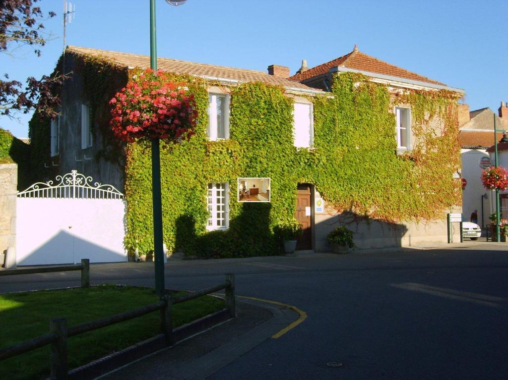 a building covered in green ivy on a street at Lalobema in Machecoul