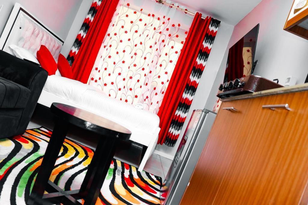 a living room with a chair and a red curtain at Maven Sparkles Furnished Apartments in Kiambu