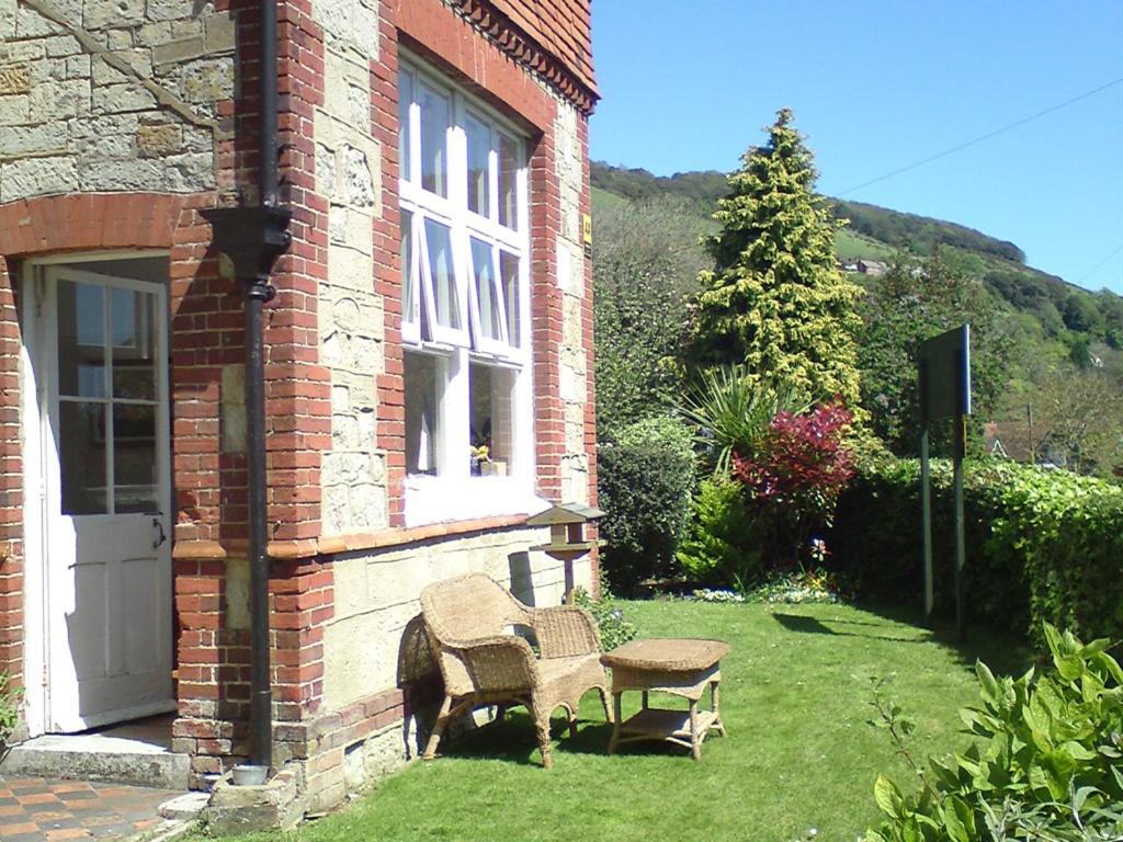 a house with a chair and a table in the yard at Cornerways in Ventnor
