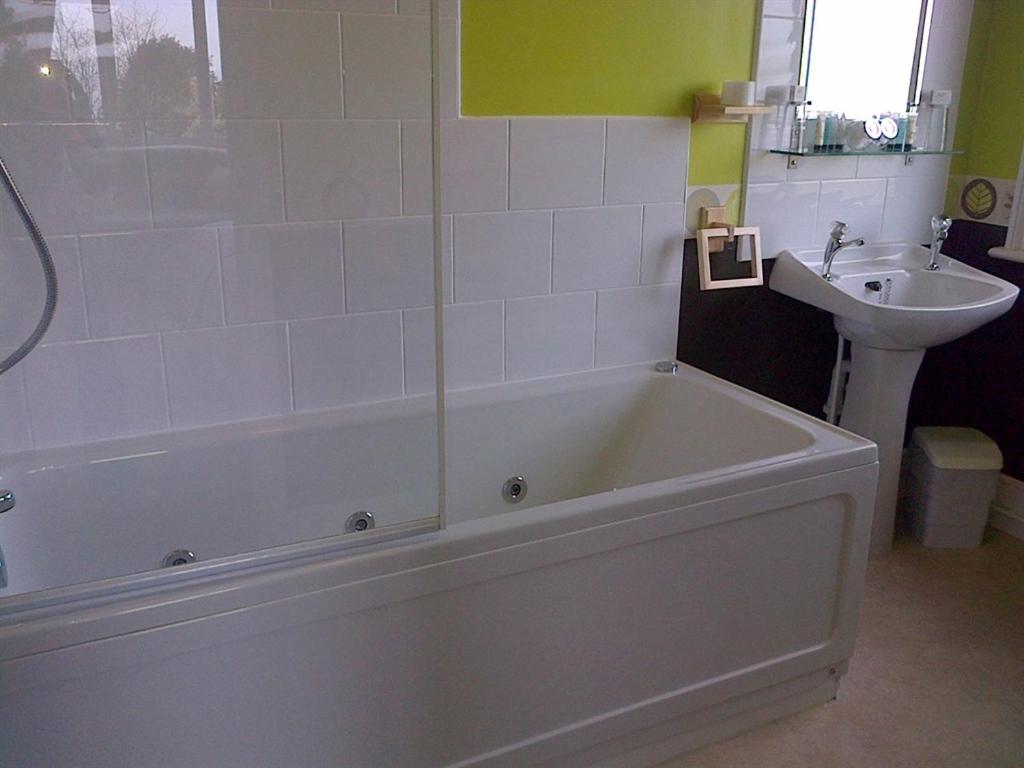 a bathroom with a bath tub and a sink at Cornerways in Ventnor
