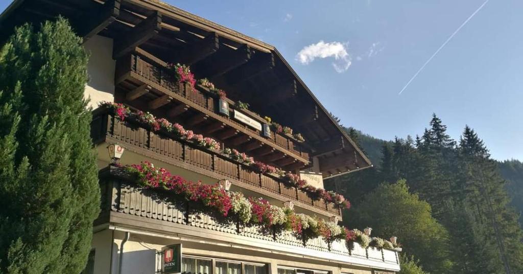 a building with flowers on the balconies of it at Gasthof Pension Kohlplatzl in Hopfgarten in Defereggen