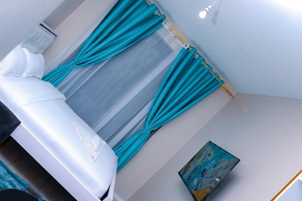 a bedroom with a window with blue curtains at Maven Glow Elegant Studios in Kiambu