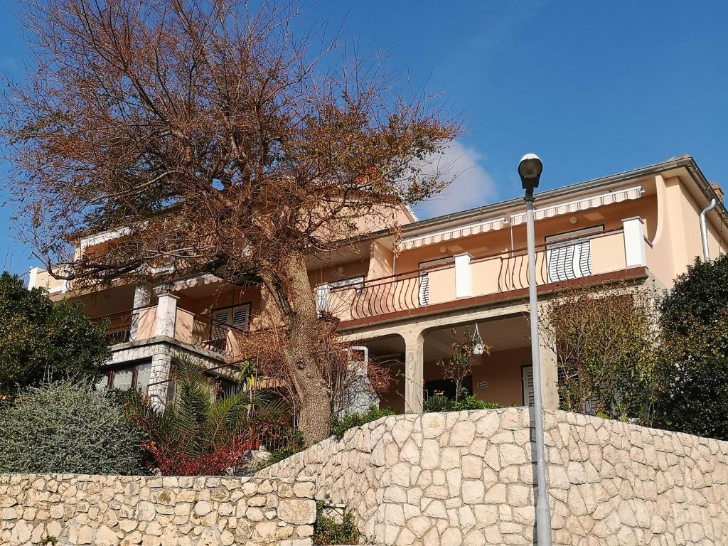 a large house with a stone wall and a tree at House Maca in Palit