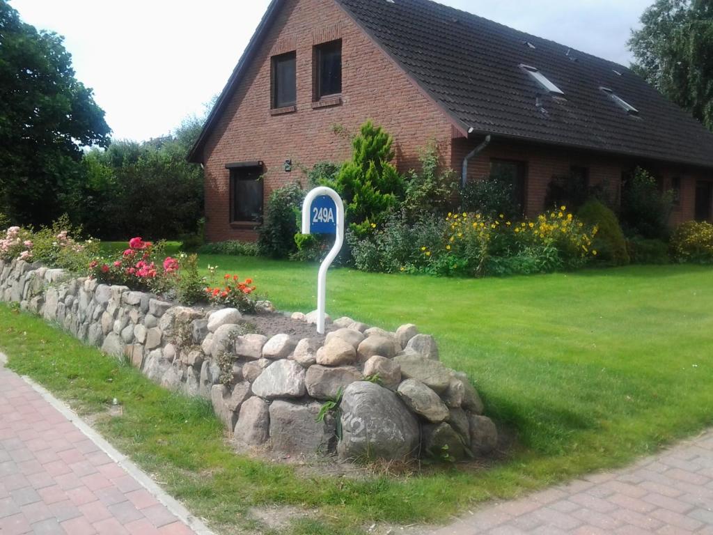 a street sign in a yard next to a stone wall at Ferienwohnung Karen&Lemmi in Risum-Lindholm